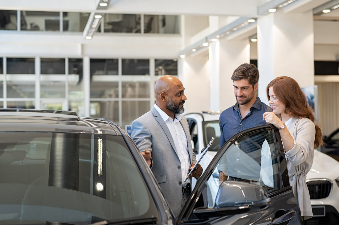 Couple Examining New Auto with Car Dealer